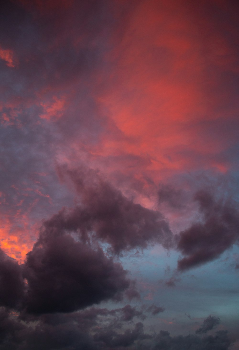 a plane flying through a cloudy sky at sunset