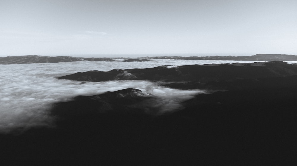 a black and white photo of clouds and mountains