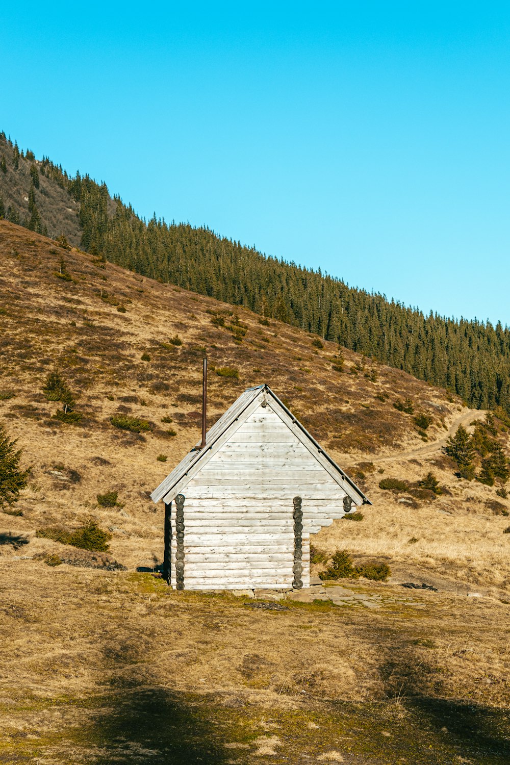 a small white building sitting in the middle of a field