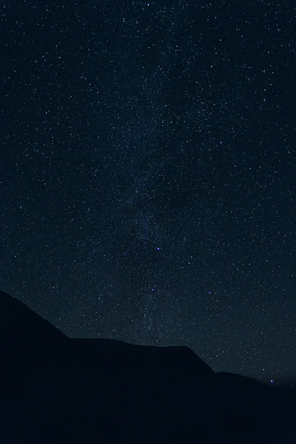 the night sky with stars above a mountain