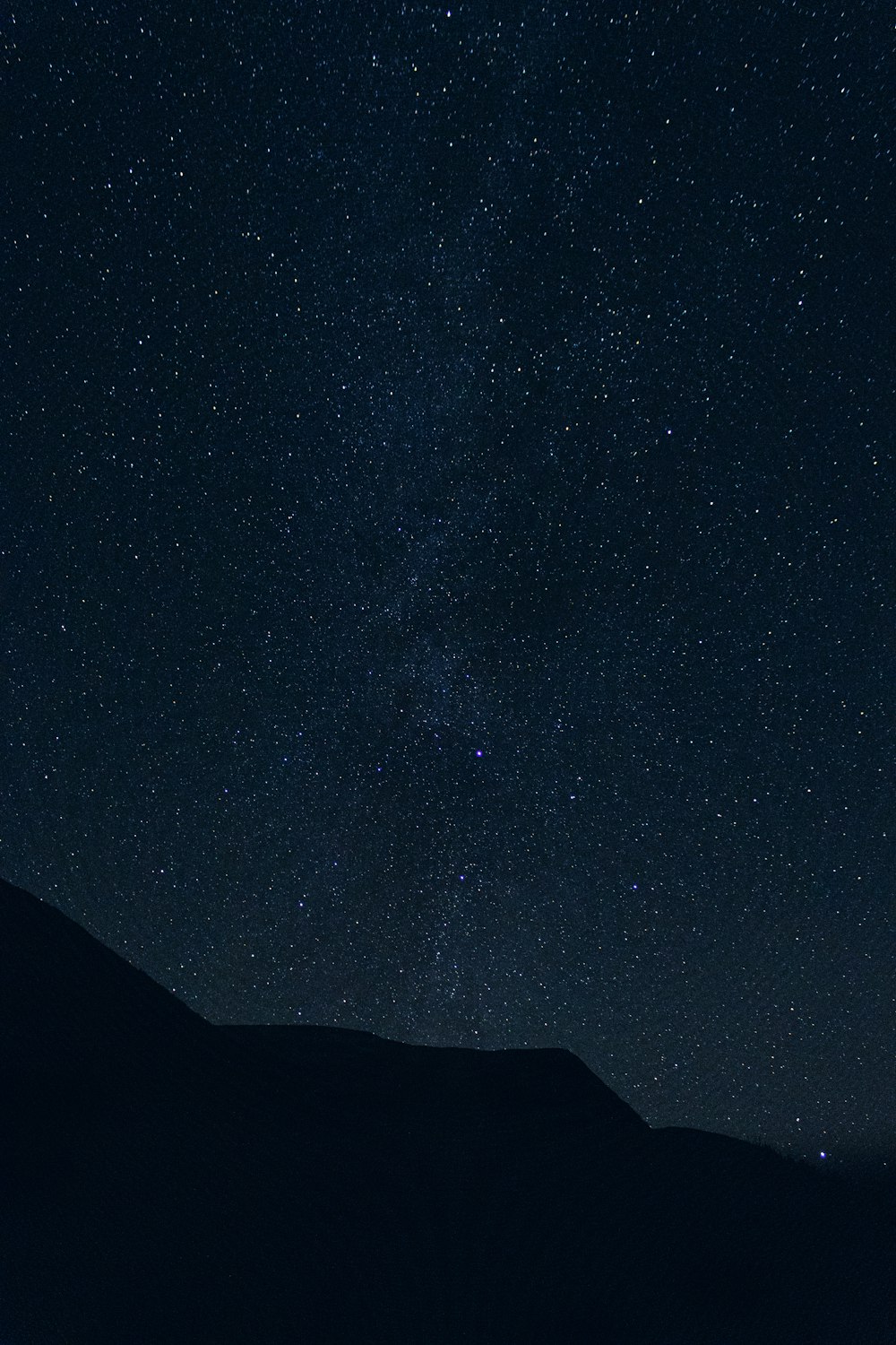 o céu noturno com estrelas acima de uma montanha