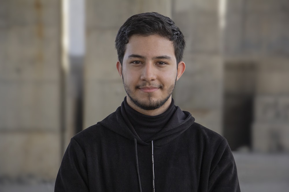 a man in a black hoodie standing in front of a building