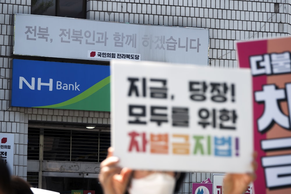 a group of people holding up signs in front of a building