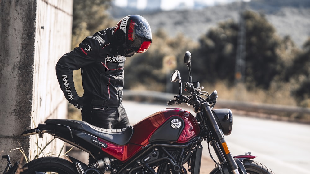 a man standing next to a red motorcycle