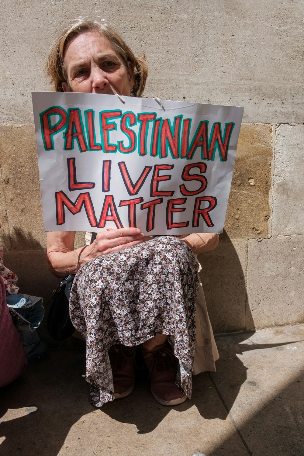 a woman sitting on the ground holding a sign