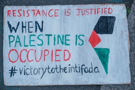a sign on a sidewalk that says resistance is justified