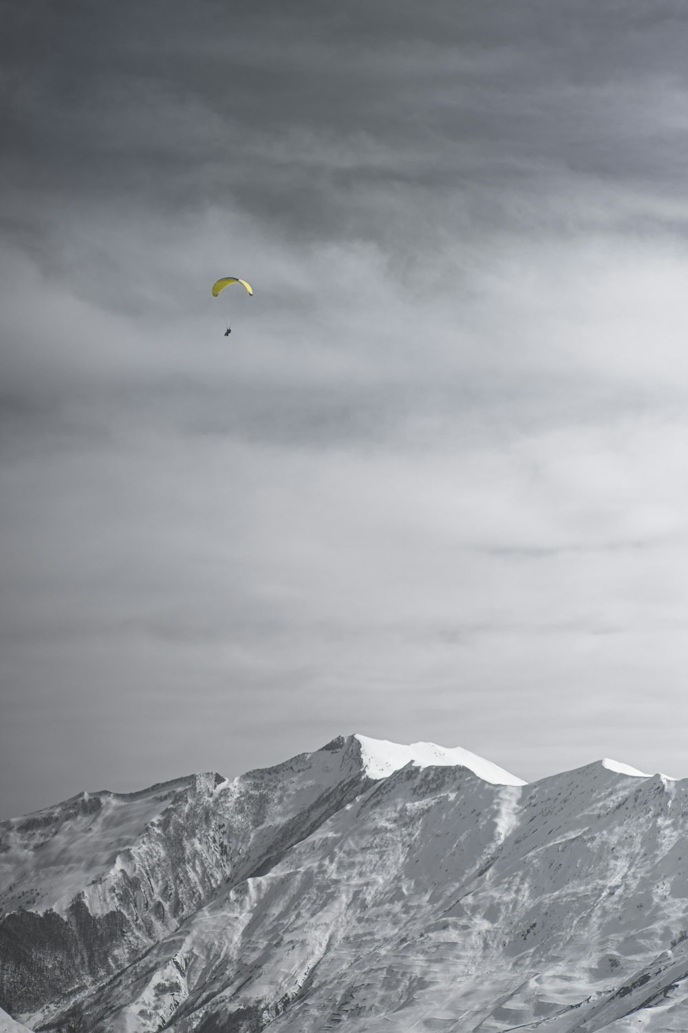 a paraglider is flying over a snowy mountain range