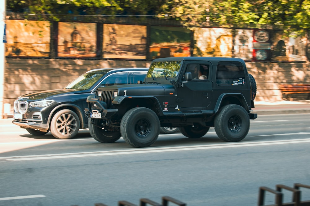 a black jeep driving down a street next to a building