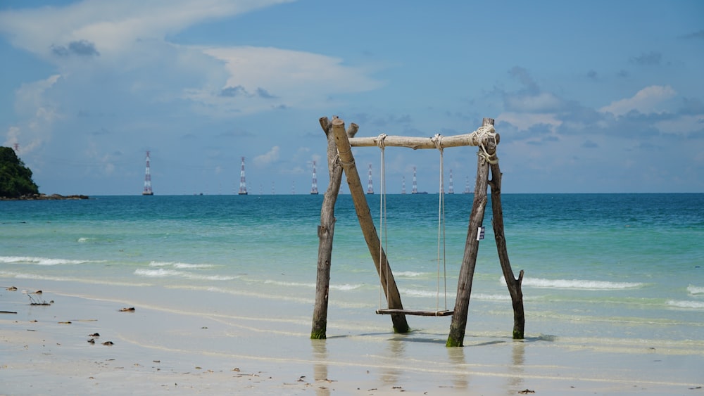 a wooden swing sitting on top of a sandy beach