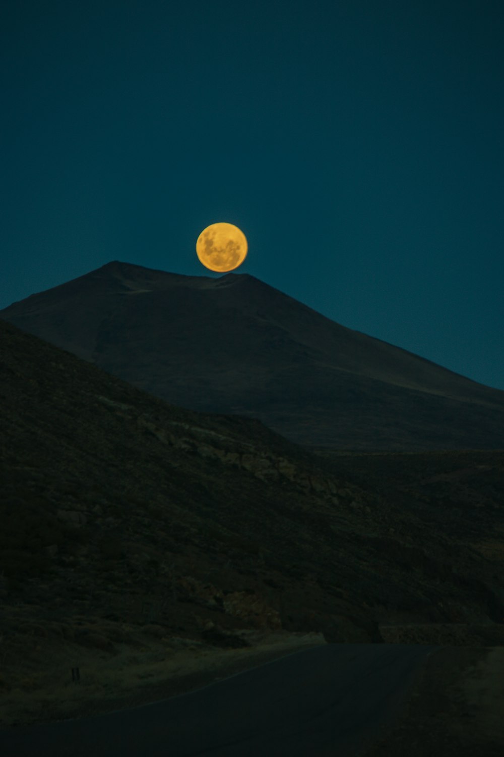 a full moon rising over a mountain range