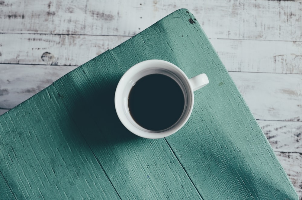 a cup of coffee sitting on top of a wooden table