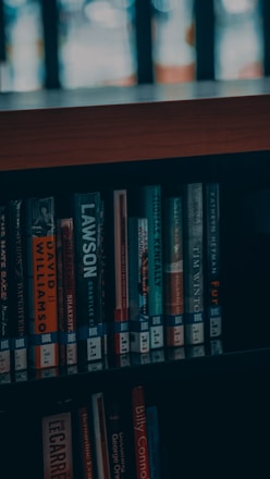 a bookshelf filled with lots of books next to a window