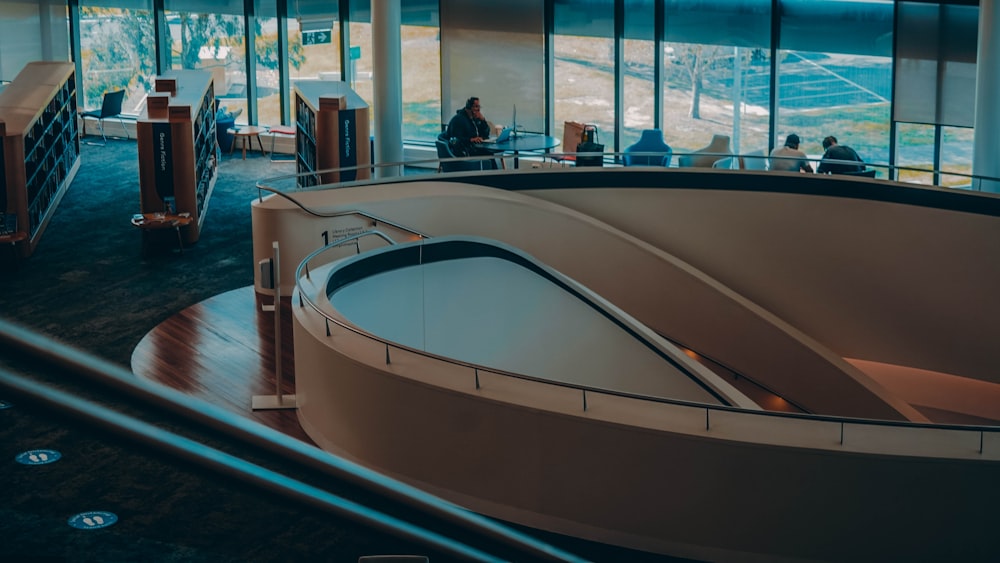 a curved staircase inside of a building with people sitting at tables