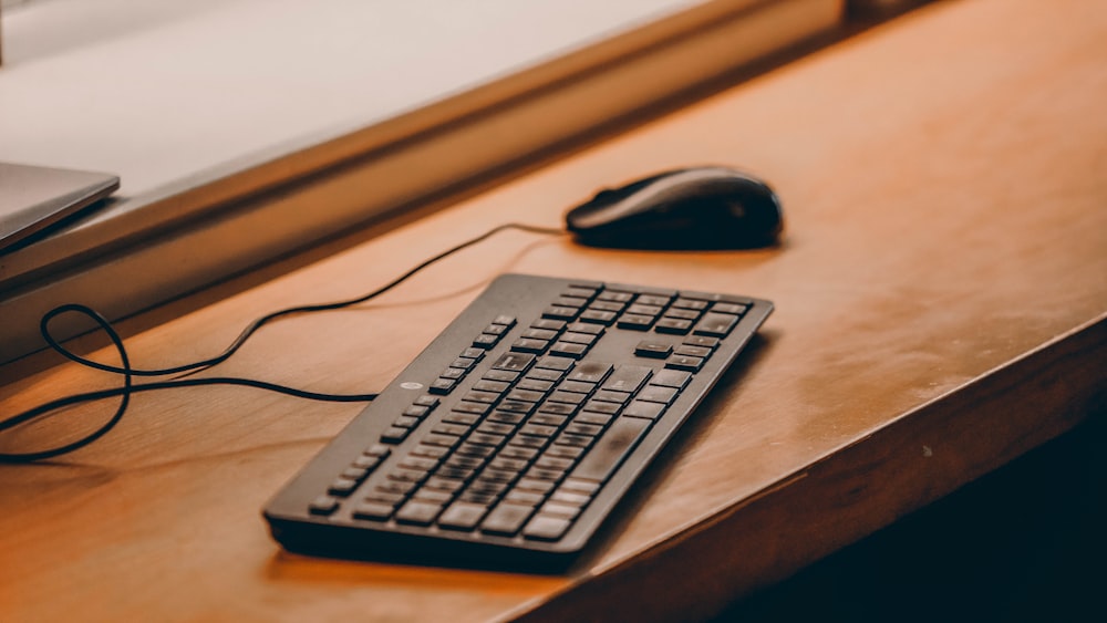 a computer keyboard and mouse on a desk