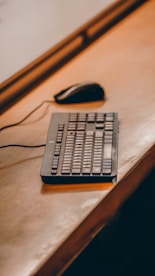 a computer keyboard sitting on top of a wooden desk