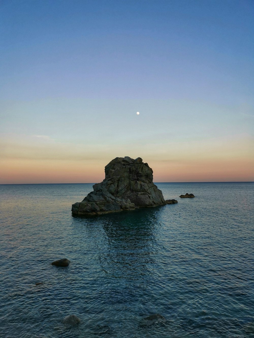 uma grande rocha sentada no meio de um corpo de água
