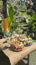 A person arranging traditional paper offerings on a wooden table outdoors.