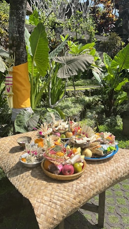 Colorful offerings arranged carefully on a stone altar, surrounded by tropical flowers.