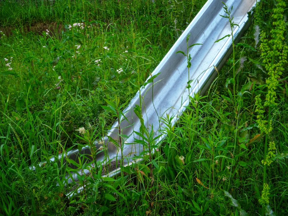 a metal slide laying in a field of tall grass