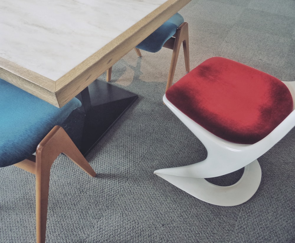 a white table with a red seat next to a blue chair