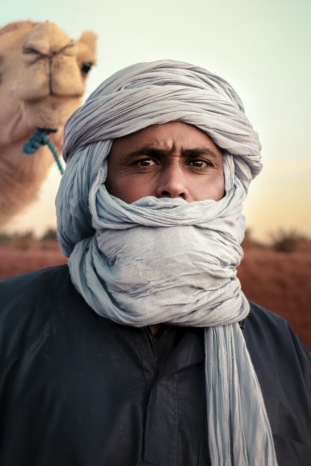a man in a turban with a camel in the background