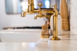 a bathroom sink with a gold faucet next to it