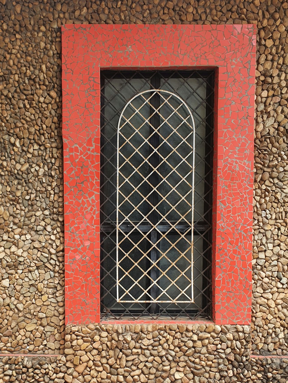 a stone wall with a red window and a black window pane