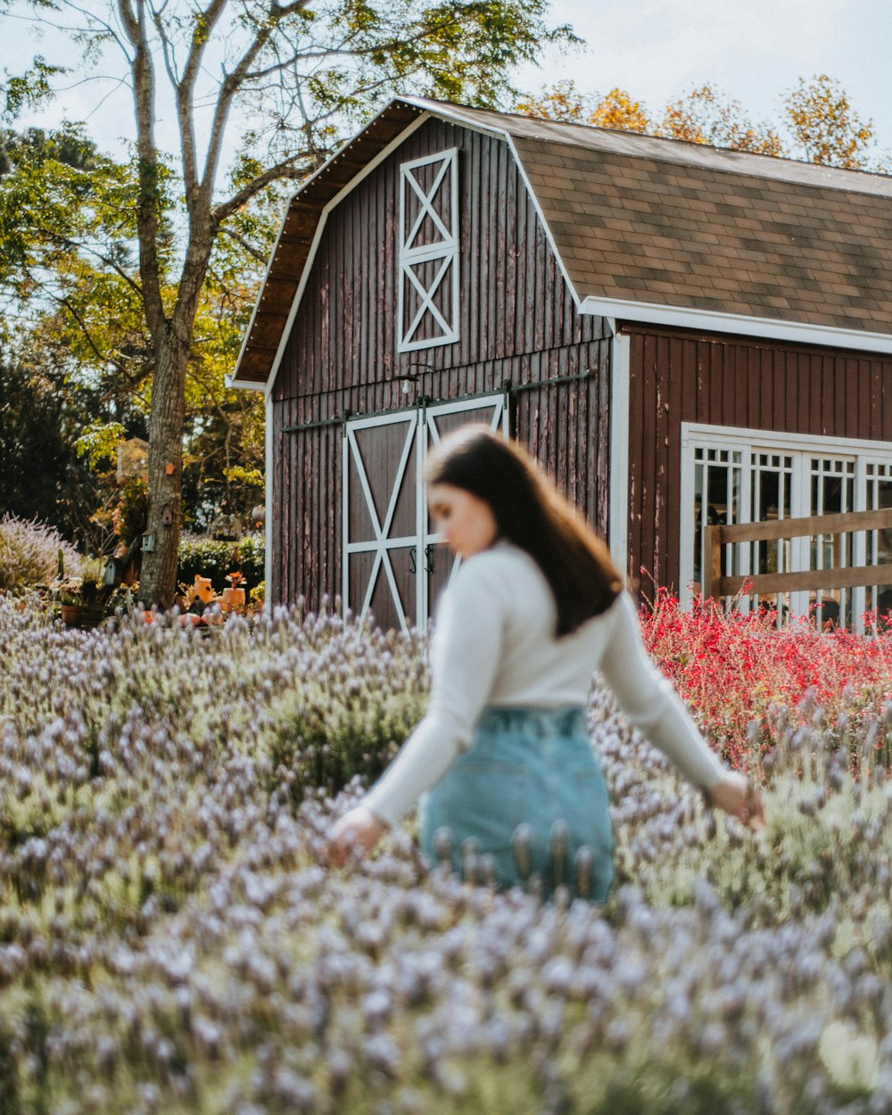 a woman walking through a field of flowers