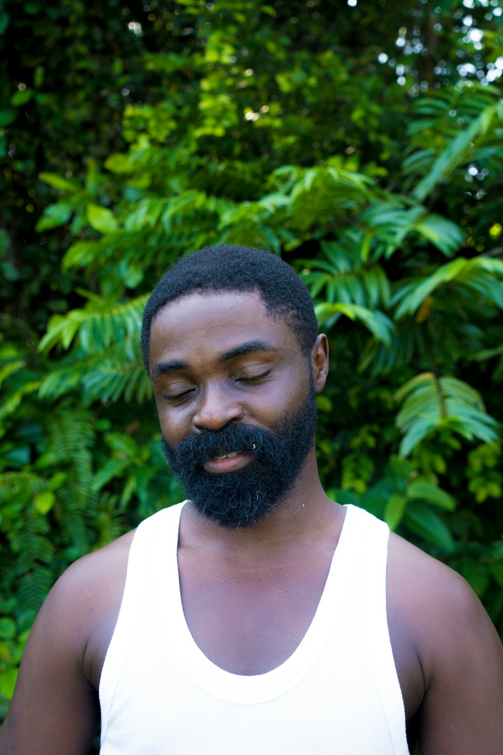 a man with a beard and a white tank top