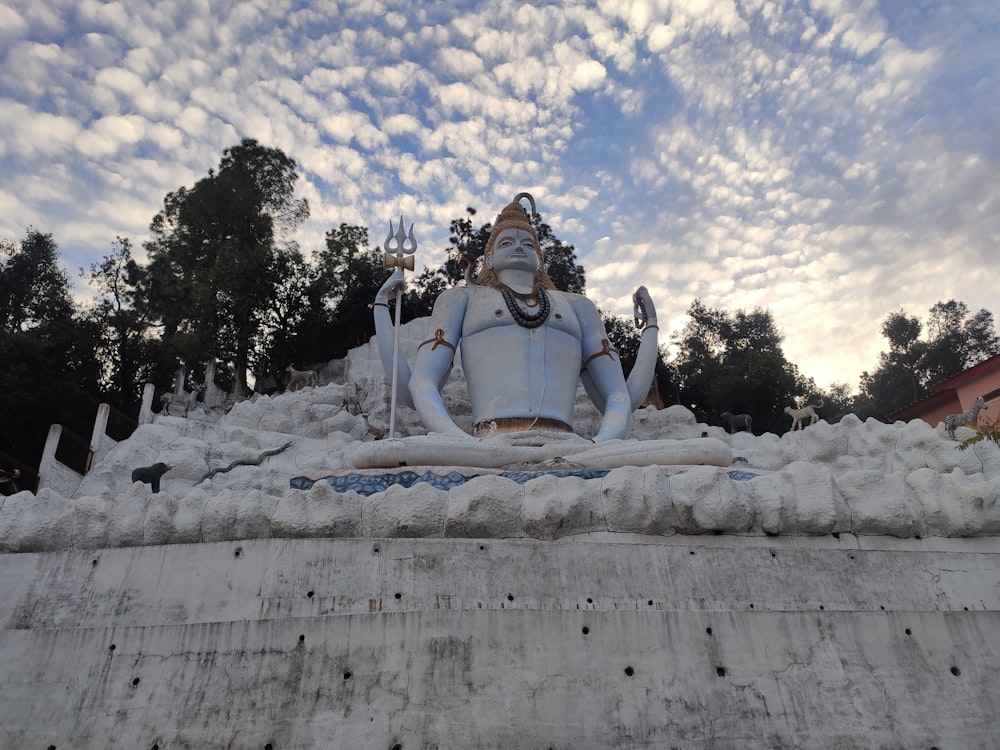 a statue of a person sitting in front of a cloudy sky