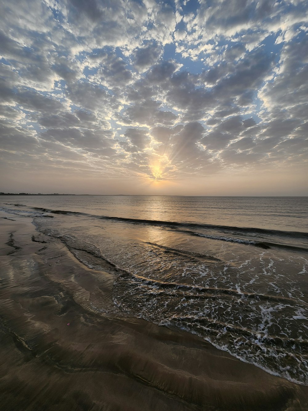 the sun is setting over the ocean on the beach