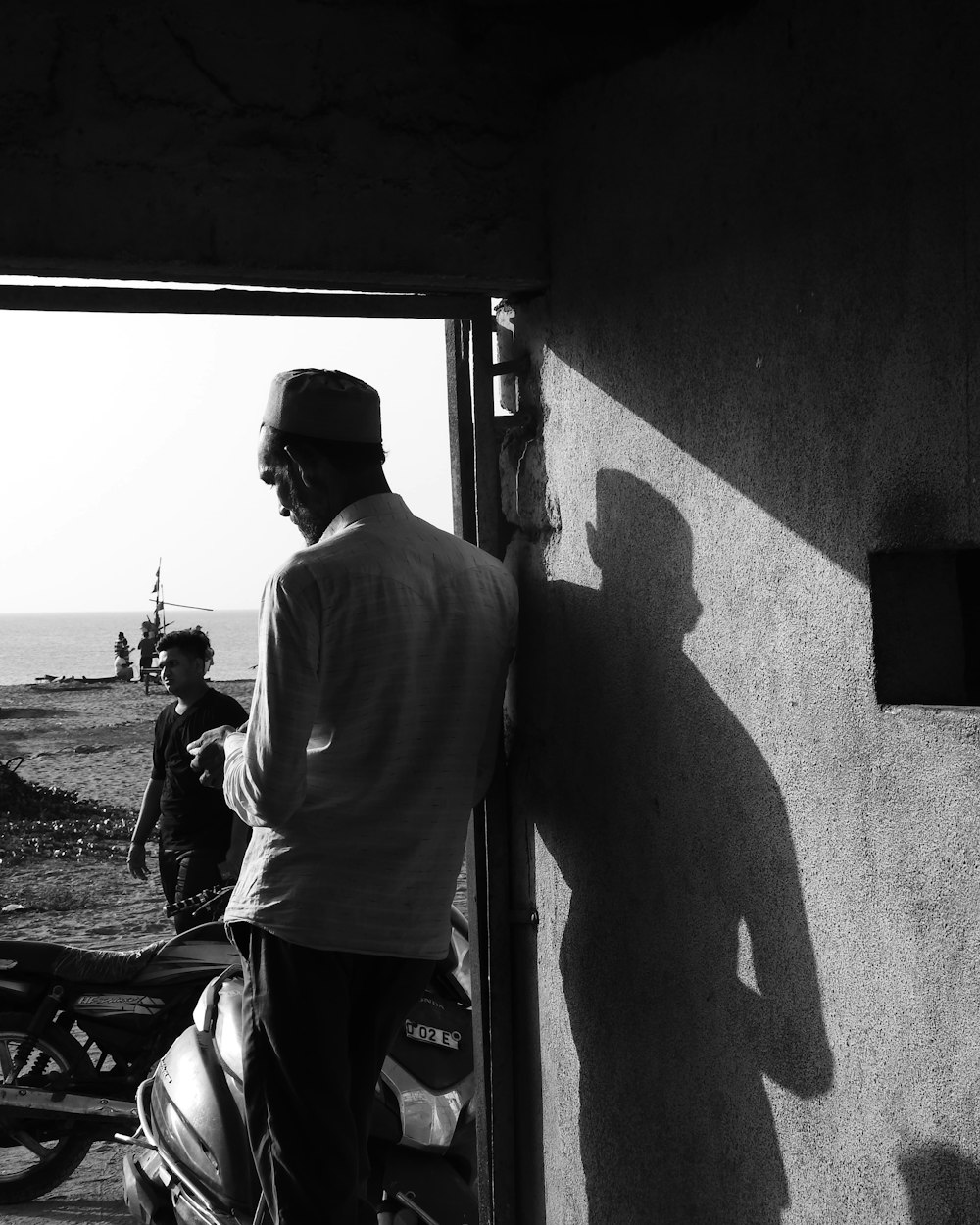 a black and white photo of a man standing next to a motorcycle