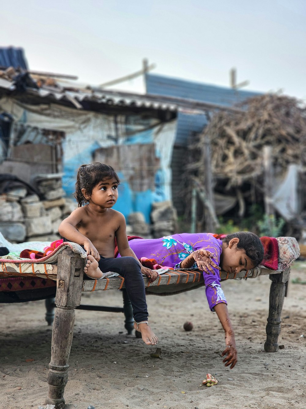 a couple of kids laying on top of a wooden bench