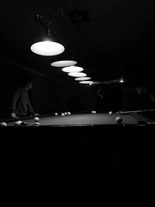 Professional-grade pool table with players enjoying a friendly game during league night.