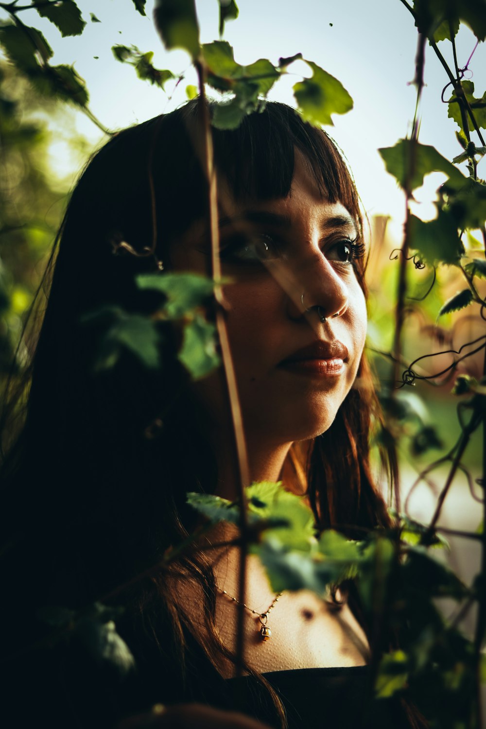 a woman with long hair standing in front of a tree