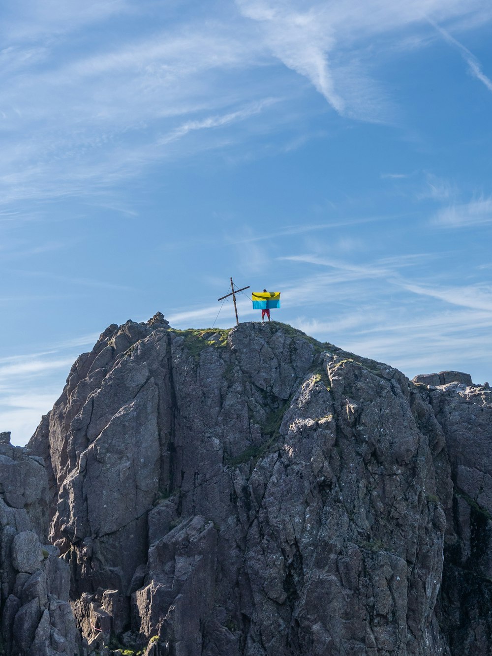 uma pessoa em pé no topo de uma montanha com uma cruz