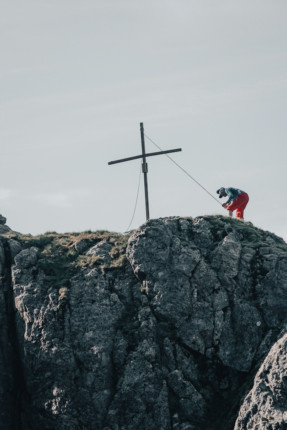 a person on a rock with a cross on top of it