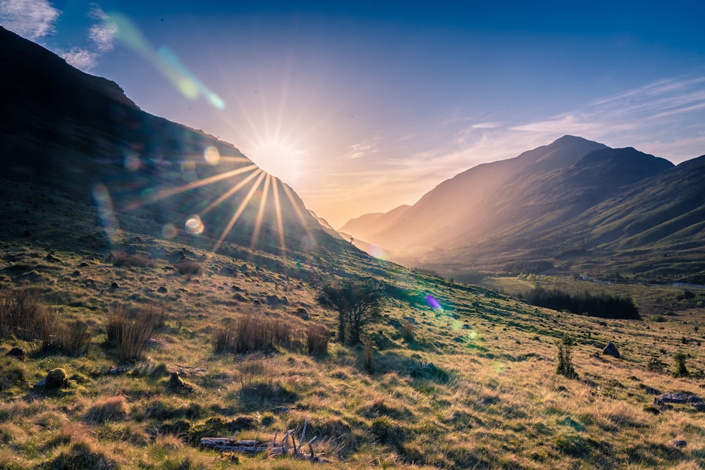 the sun shines brightly over a mountain valley