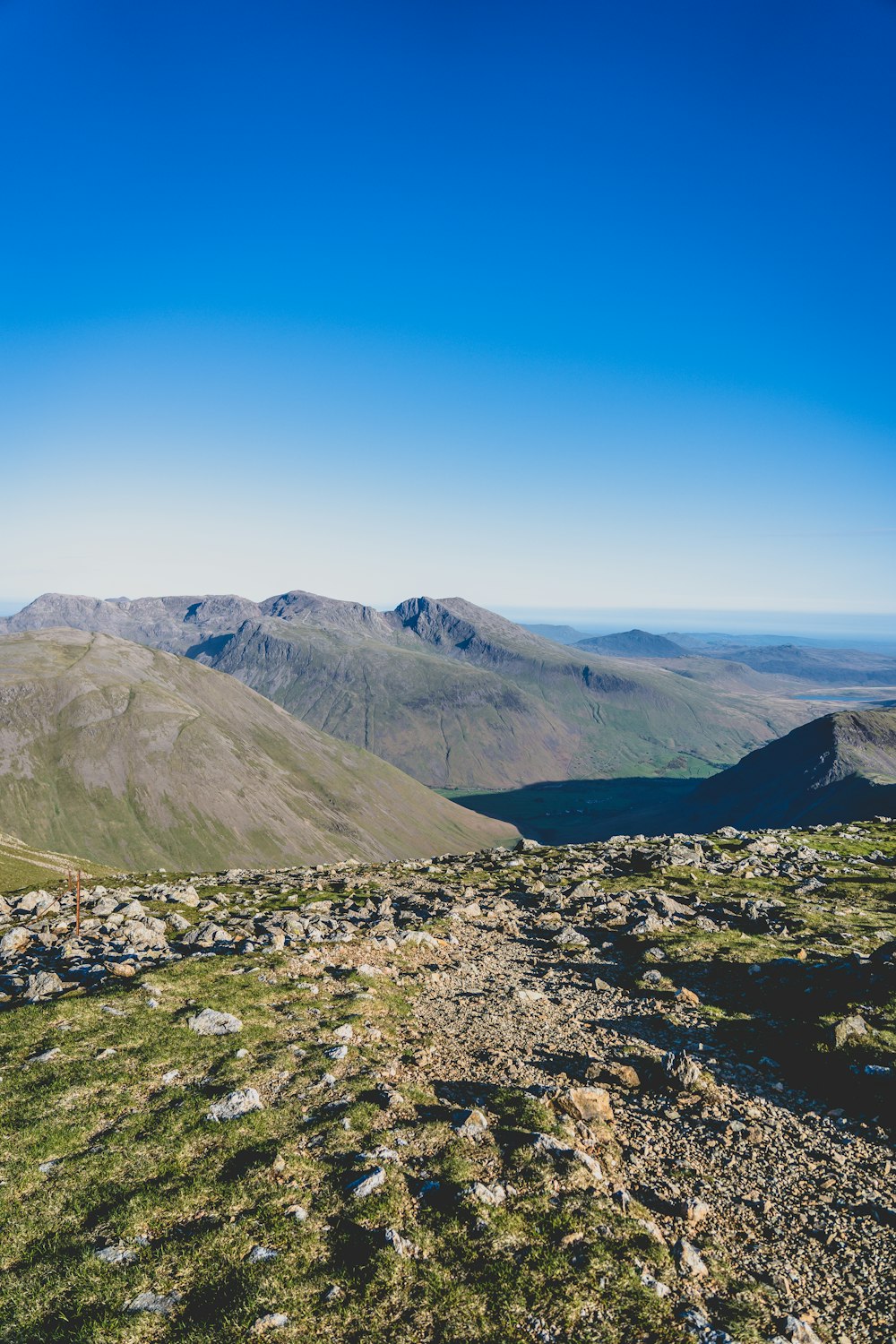 a view of a mountain range from a grassy hill