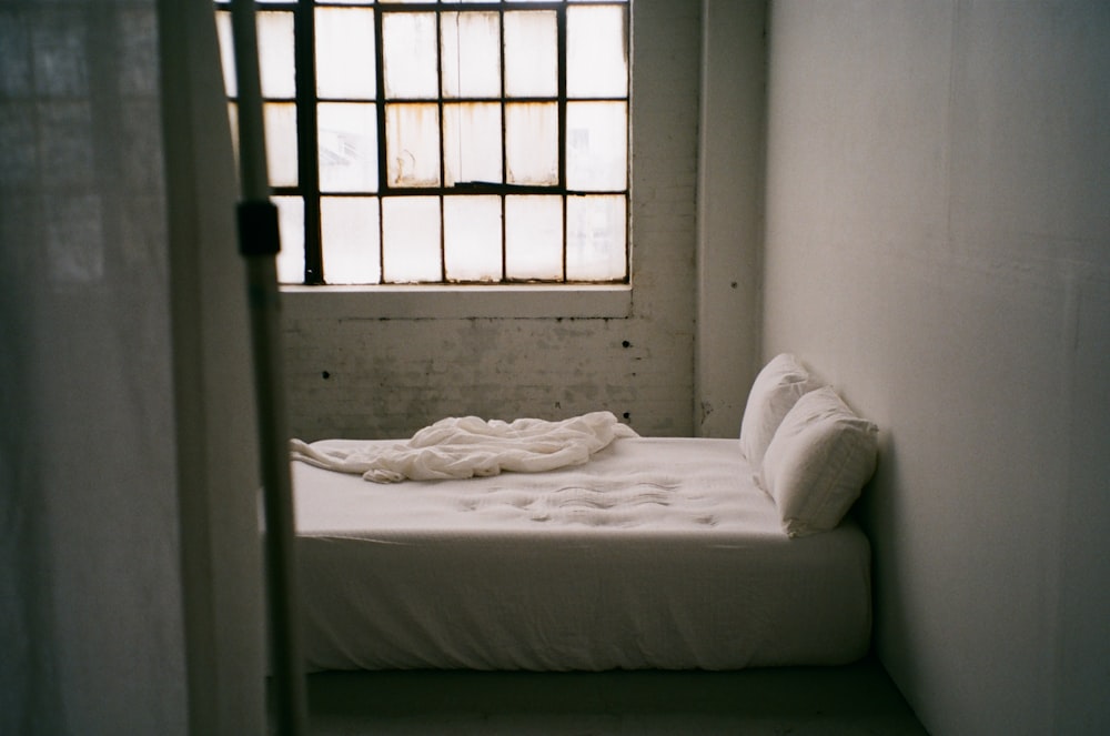 a small bed in a small room with a window