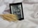 An e-reader displaying the cover of a book titled 'Sorcery of Thorns' by Margaret Rogerson rests on a soft, white fabric. A stalk of wheat is positioned beside the e-reader, adding a natural element to the scene. The color scheme of the e-book cover is primarily grayscale.