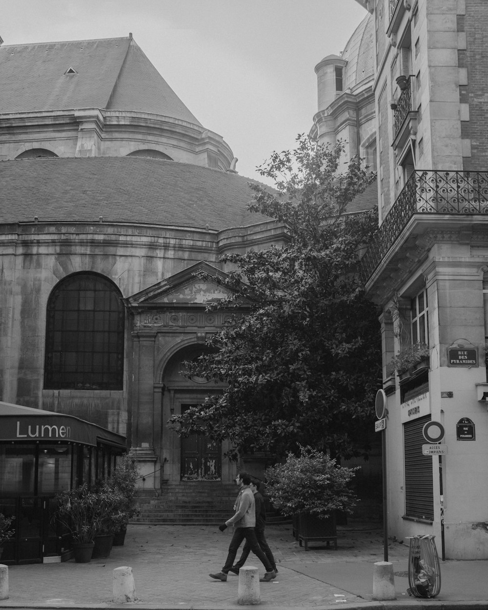 a black and white photo of a person walking in front of a building