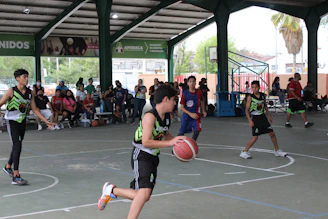 Young players practicing precise footwork drills on a bright indoor basketball court.