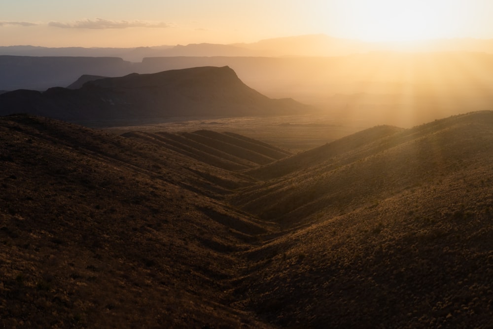 the sun is setting over a mountain range