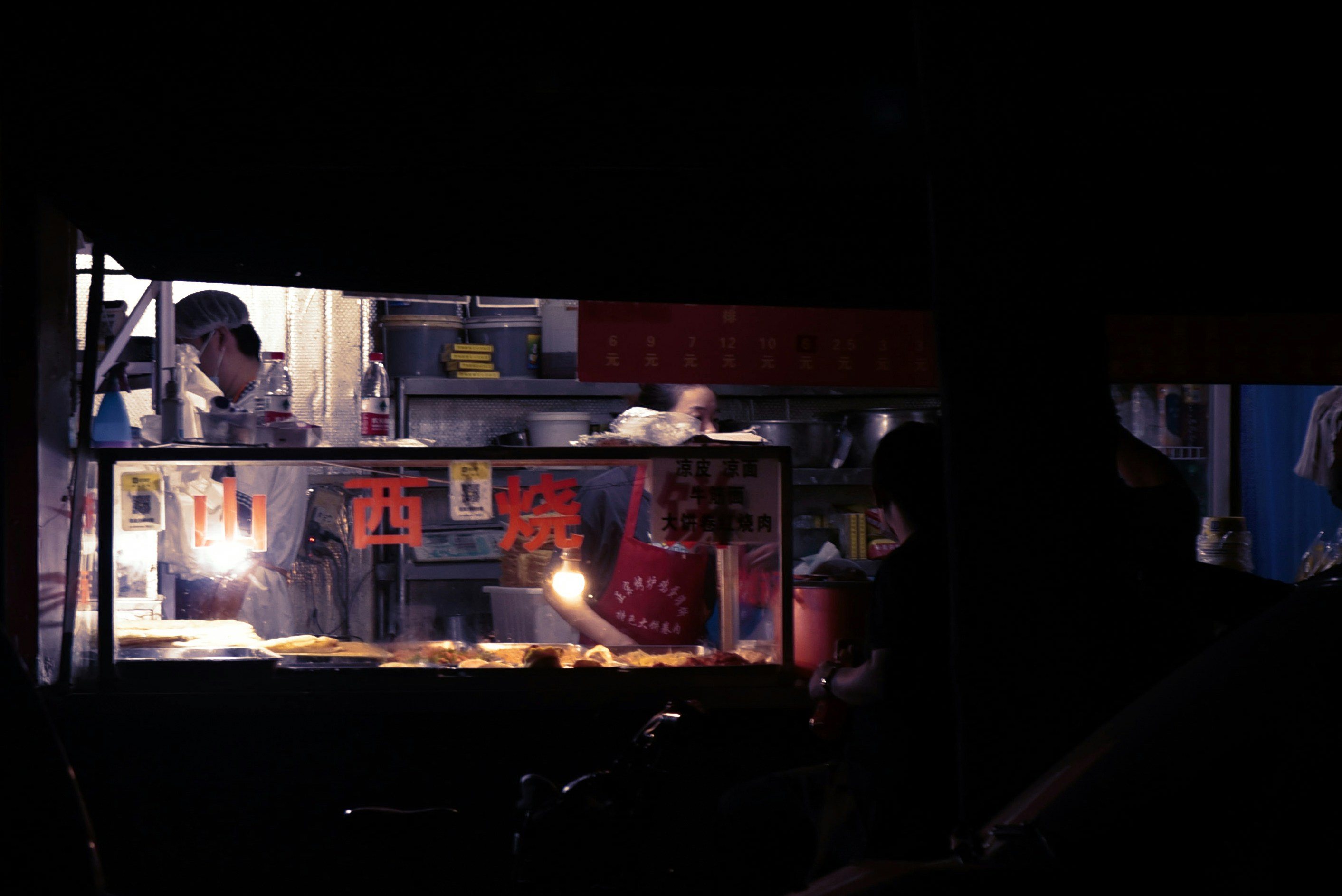 a man cooking food in a kitchen at night