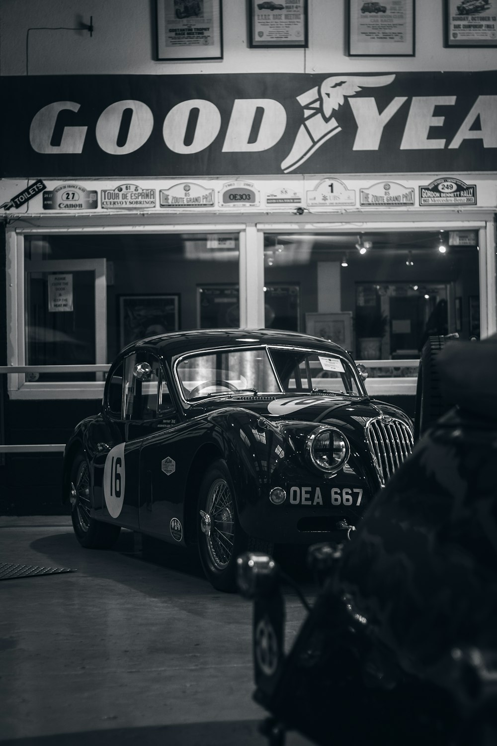 a black and white photo of a car parked in front of a store