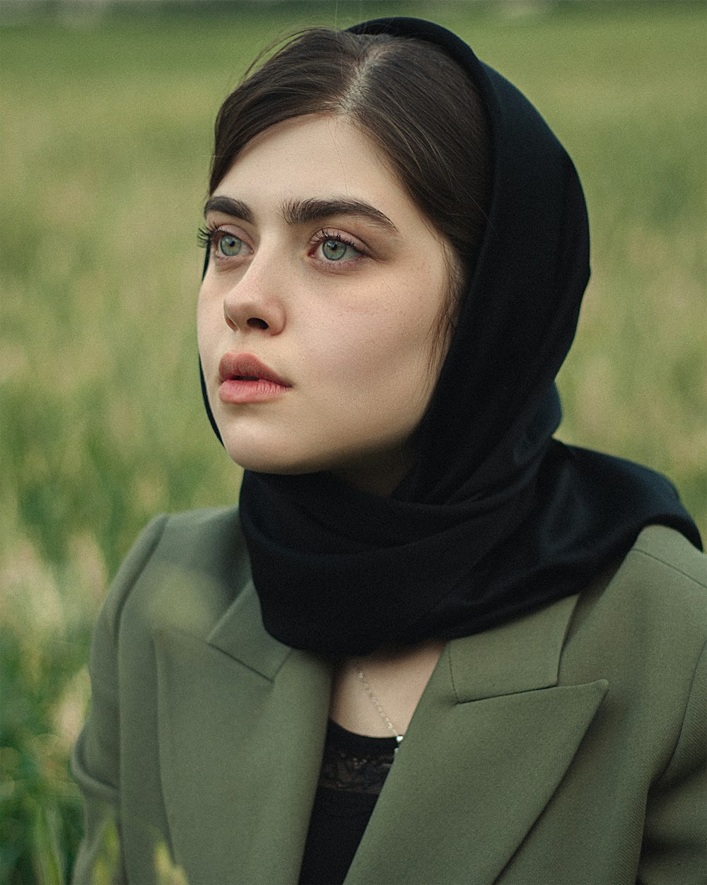a woman wearing a green coat and a black scarf