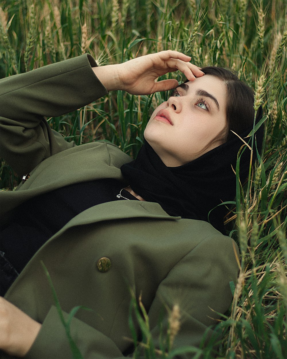 a woman laying in a field of tall grass