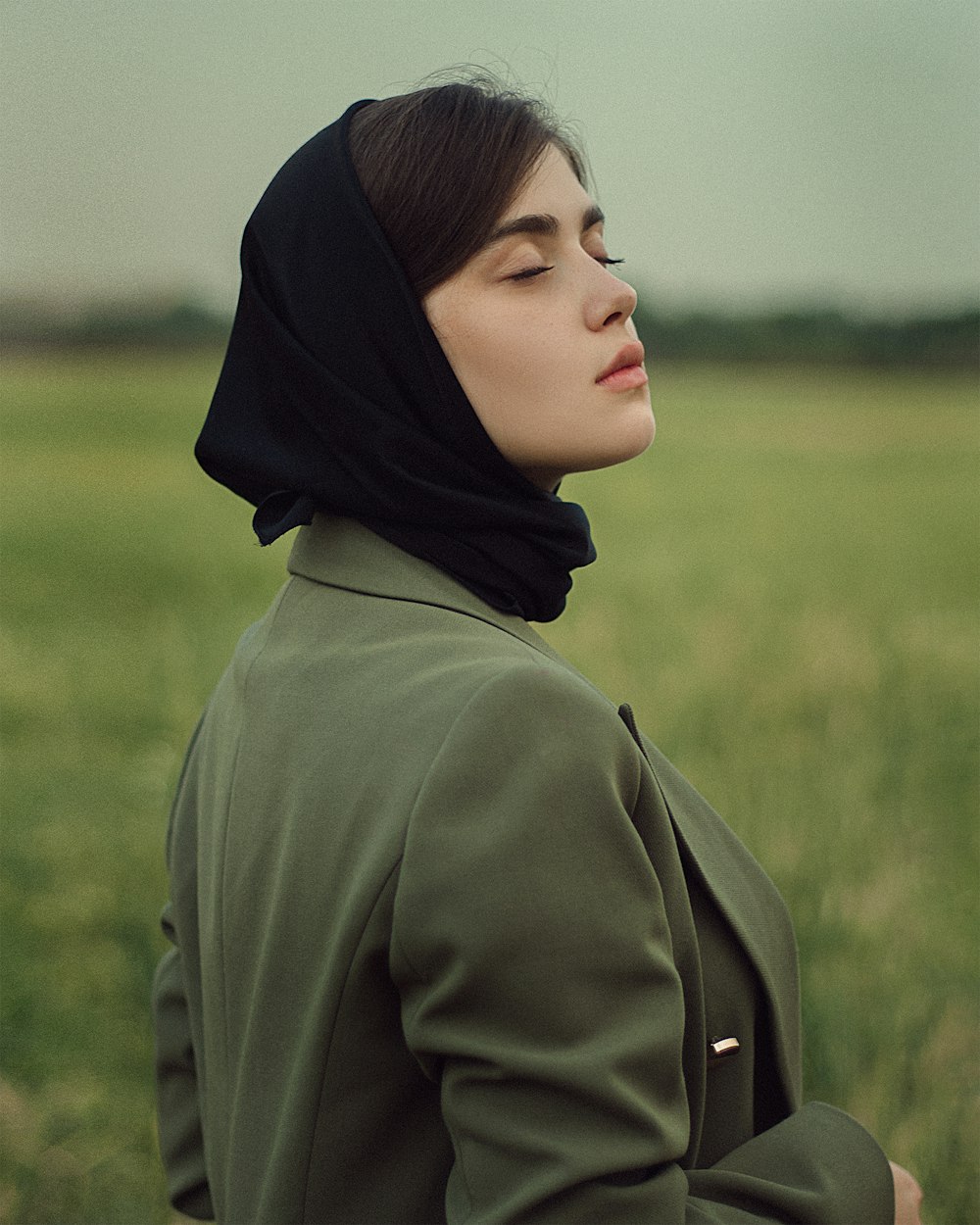 a woman in a green jacket standing in a field