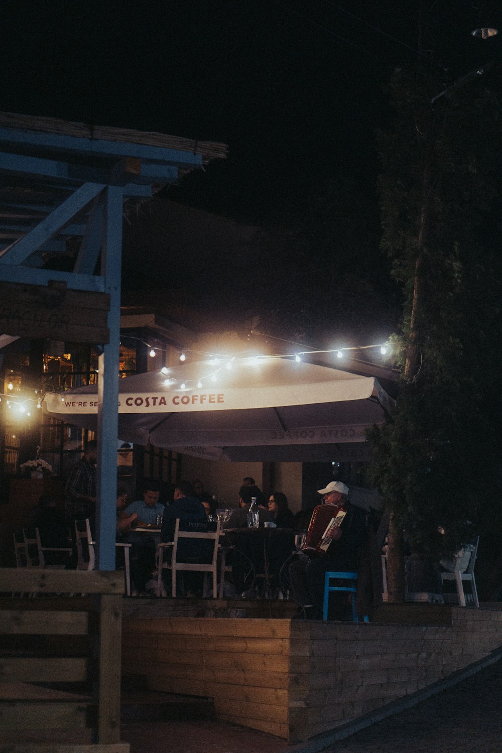 a group of people sitting at a table under an umbrella